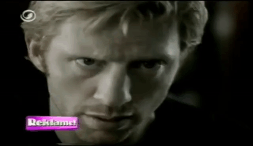 A Close Up Of A Man 'S Face With A Purple Sign That Says Reklama GIF