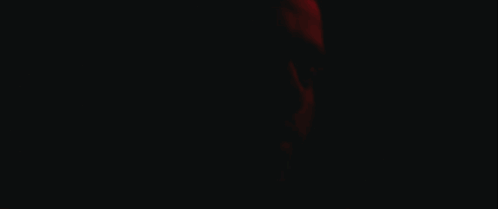 A Close Up Of A Man 'S Face With A Red Light Behind Him GIF