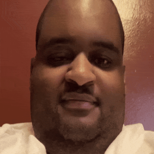 a close up of a man 's face with a red wall behind him