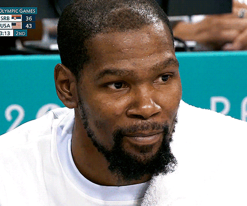 A Close Up Of A Man 'S Face With A Scoreboard Behind Him That Says Olympic Games In Blue GIF
