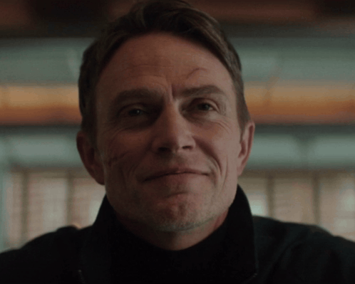 A Close Up Of A Man 'S Face With A Slight Smile On His Face GIF