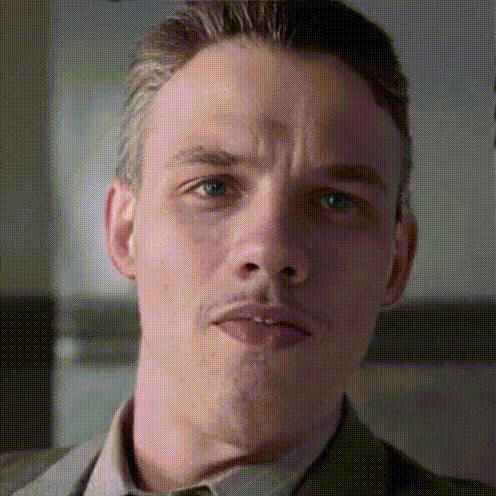 A Close Up Of A Man 'S Face With A Slight Smirk On His Face GIF