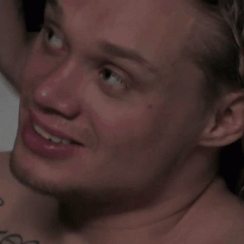A Close Up Of A Man 'S Face With A Tattoo On His Shoulder GIF