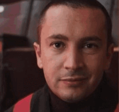 A Close Up Of A Man 'S Face With A Turtleneck And A Scarf Around His Neck . GIF