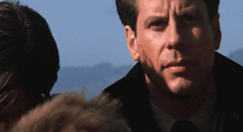 A Close Up Of A Man 'S Face With A Woman Behind Him GIF