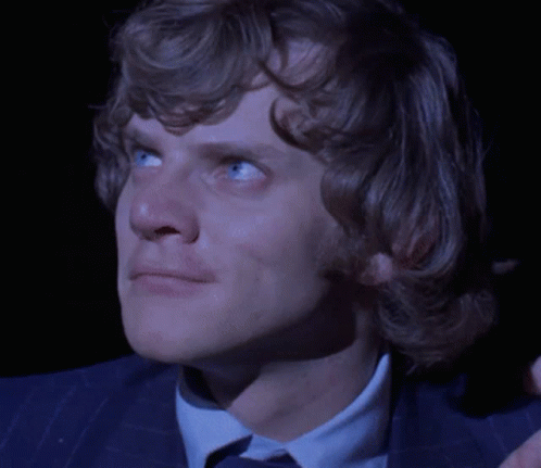 A Close Up Of A Man 'S Face With Blue Eyes And A Blue Suit GIF