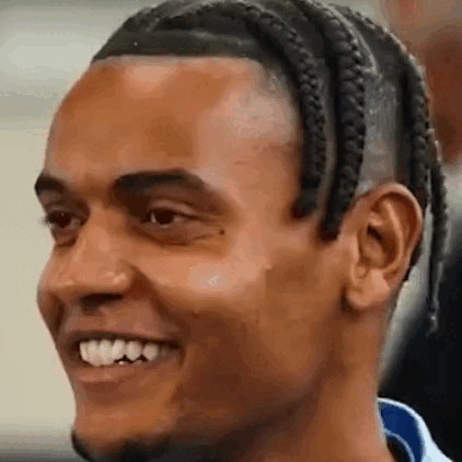 A Close Up Of A Man 'S Face With Braids And A Beard Smiling . GIF