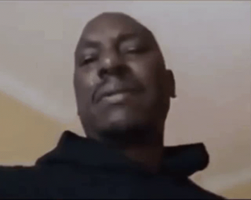 A Close Up Of A Man 'S Face With His Eyes Closed And A Black Hoodie On . GIF