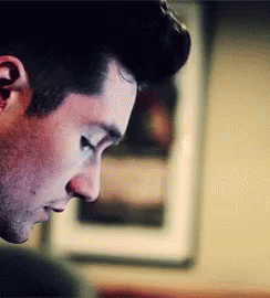 A Close Up Of A Man 'S Face With His Eyes Closed Looking Down . GIF