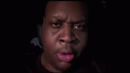 A Close Up Of A Man 'S Face With His Finger On His Mouth . GIF