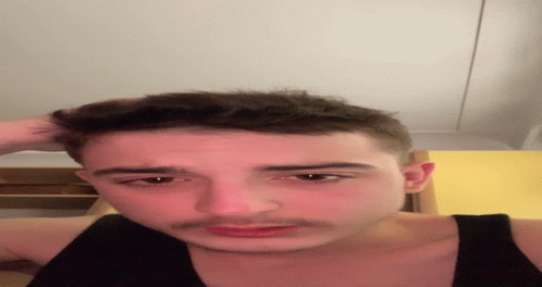 A Close Up Of A Man 'S Face With His Hand On His Head GIF