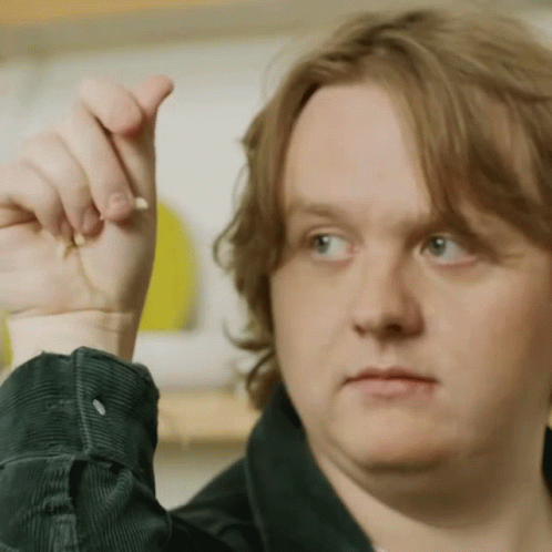A Close Up Of A Man 'S Face With His Hand Up In The Air GIF