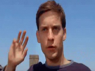 A Close Up Of A Man 'S Face With His Hand Up In The Air . GIF
