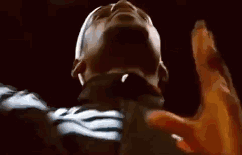 a close up of a man 's face with his hands up in the air .