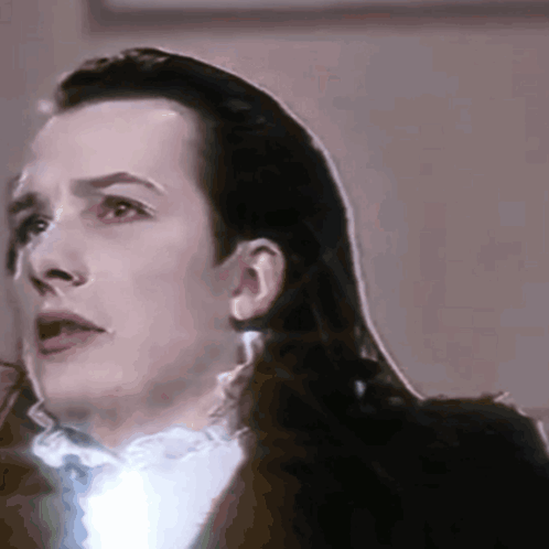 A Close Up Of A Man 'S Face With Long Hair And A White Shirt GIF