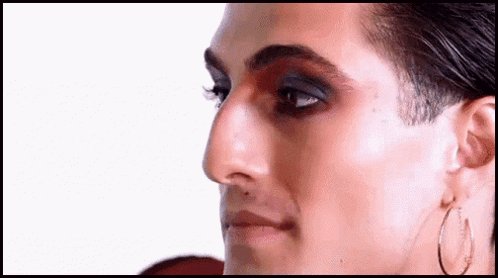 A Close Up Of A Man 'S Face With Makeup And Hoop Earrings On . GIF