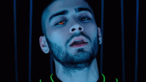 A Close Up Of A Man 'S Face With Red Eyes And A Beard In A Dark Room . GIF
