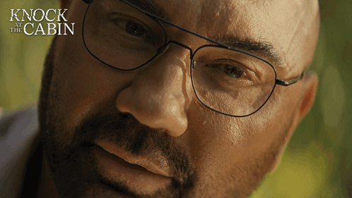 A Close Up Of A Man 'S Face With The Words " Knock At The Cabin " Behind Him GIF