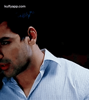A Close Up Of A Man 'S Neck And Ear In A Blue Shirt . GIF