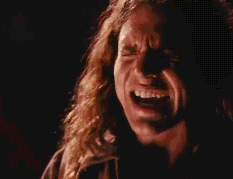 a close up of a man screaming into a microphone in a dark room .