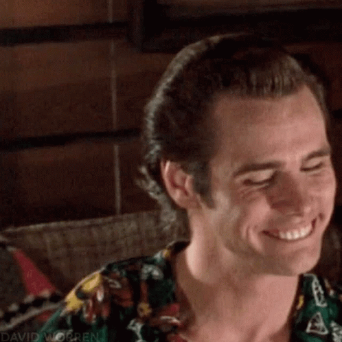 A Close Up Of A Man Smiling With His Eyes Closed And Wearing A Floral Shirt . GIF