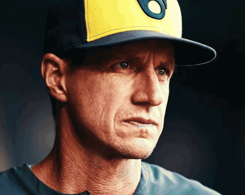a close up of a man wearing a baseball cap with the letter o on it