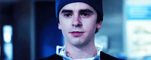 A Close Up Of A Man Wearing A Blue Beanie And A Surgical Mask . GIF
