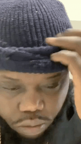 A Close Up Of A Man Wearing A Blue Knitted Hat On His Head . GIF