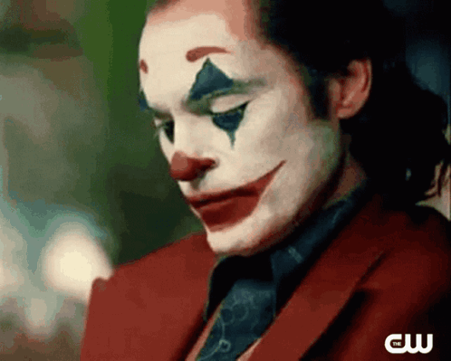 A Close Up Of A Man Wearing A Clown Costume And A Red Suit And Tie . GIF