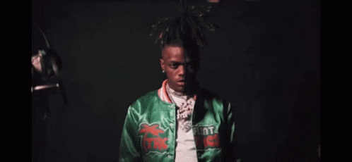 A Close Up Of A Man Wearing A Green Jacket And A Necklace . GIF