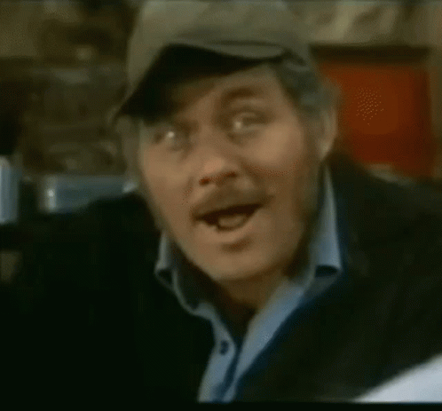 A Close Up Of A Man Wearing A Hat And A Blue Shirt GIF