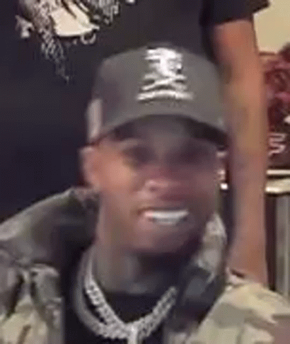 A Close Up Of A Man Wearing A Hat And A Chain . GIF