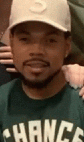 A Close Up Of A Man Wearing A Hat And A Green Shirt . GIF