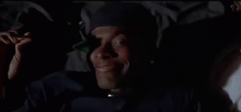 A Close Up Of A Man Wearing A Hat And A Jacket In The Dark . GIF