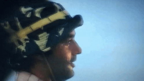A Close Up Of A Man Wearing A Helmet And Goggles Against A Blue Sky GIF