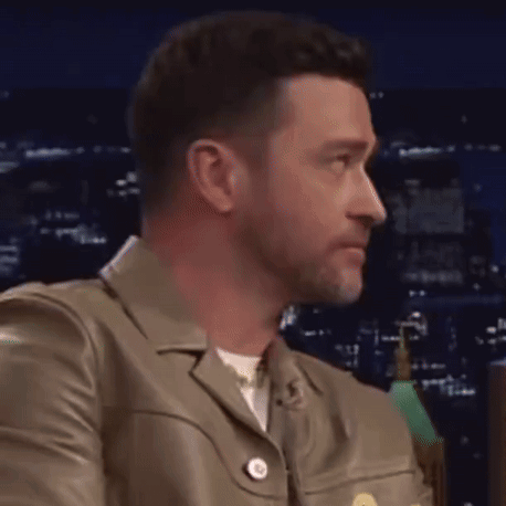A Close Up Of A Man Wearing A Leather Jacket Looking To The Side . GIF