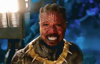 A Close Up Of A Man Wearing A Mask And A Necklace With Sharp Teeth . GIF