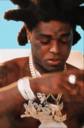 A Close Up Of A Man Wearing A Necklace With The Word Vulture On It GIF