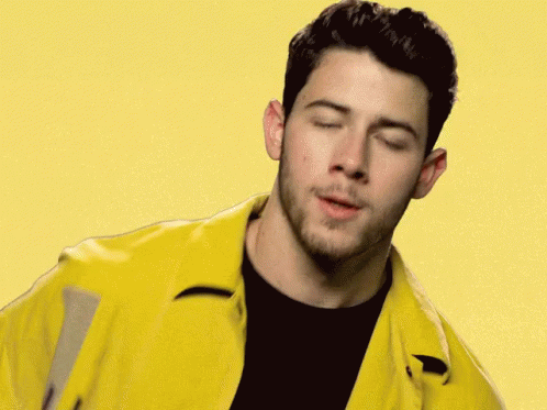 A Close Up Of A Man Wearing A Yellow Jacket And A Black Shirt With His Eyes Closed . GIF