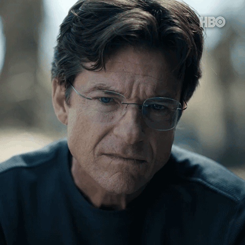 A Close Up Of A Man Wearing Glasses And A Hbo Logo In The Background GIF