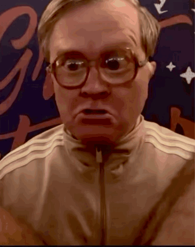A Close Up Of A Man Wearing Glasses And A Jacket With The Letter G In The Background GIF