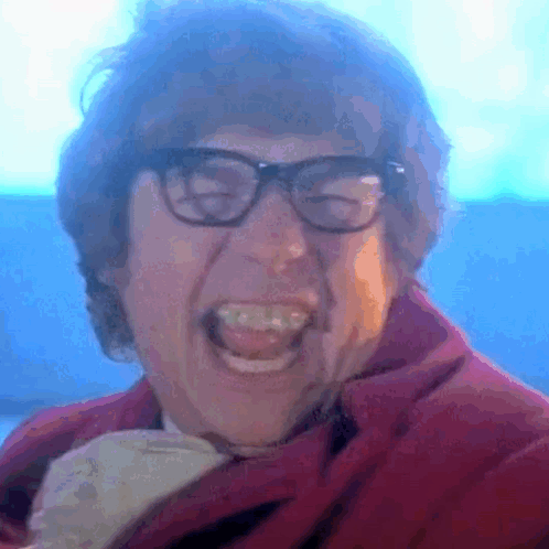 A Close Up Of A Man Wearing Glasses And A Red Jacket GIF