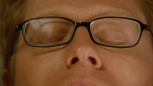 A Close Up Of A Man Wearing Glasses With His Eyes Looking Up GIF