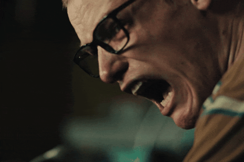A Close Up Of A Man Wearing Glasses With His Mouth Wide Open GIF