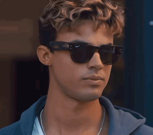 A Close Up Of A Man Wearing Sunglasses And A Blue Hoodie GIF