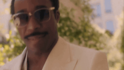 a close up of a man wearing sunglasses and a white suit .