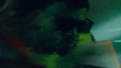 a close up of a man wearing sunglasses in the dark