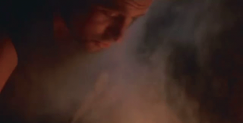A Close Up Of A Man With A Beard Smoking A Cigarette In A Dark Room . GIF
