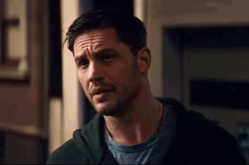 a close up of a man with a beard wearing a green hoodie and a grey t-shirt .