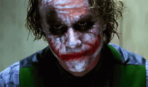 A Close Up Of A Man With A Joker Makeup On His Face Looking At The Camera . GIF